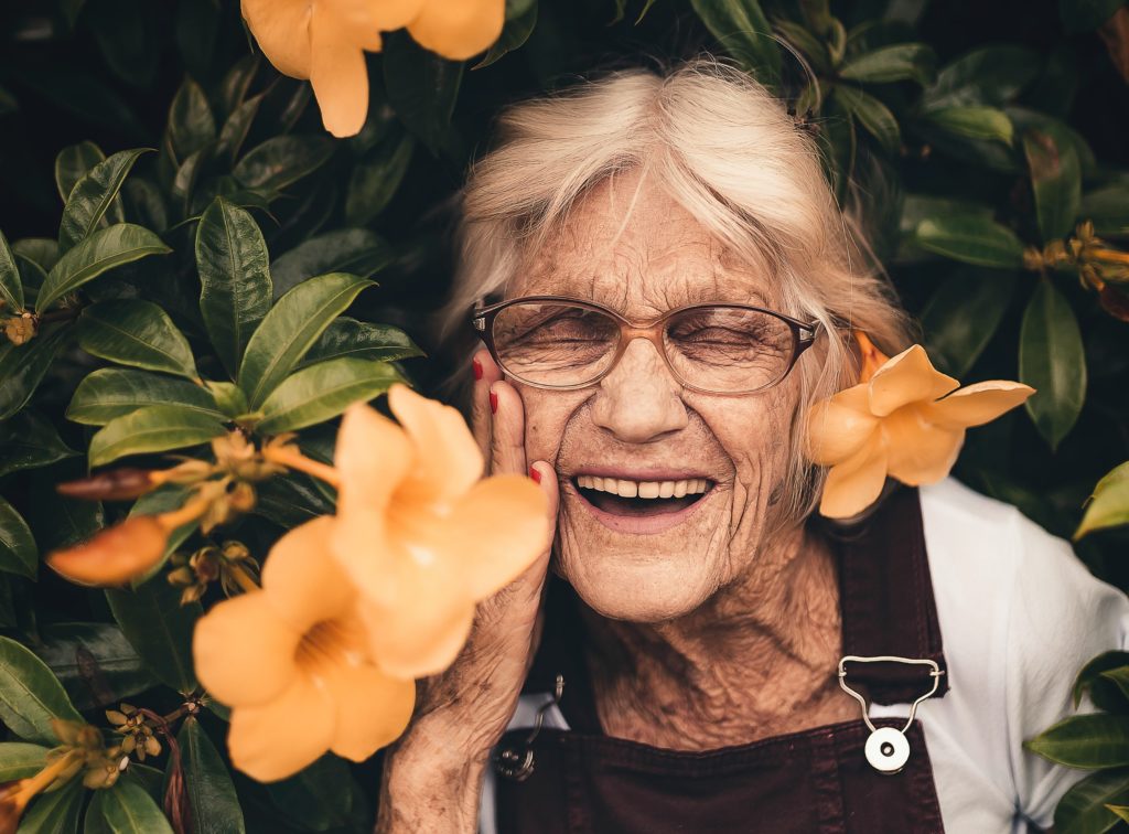 Elderly woman smiling amongst flowers in the garden